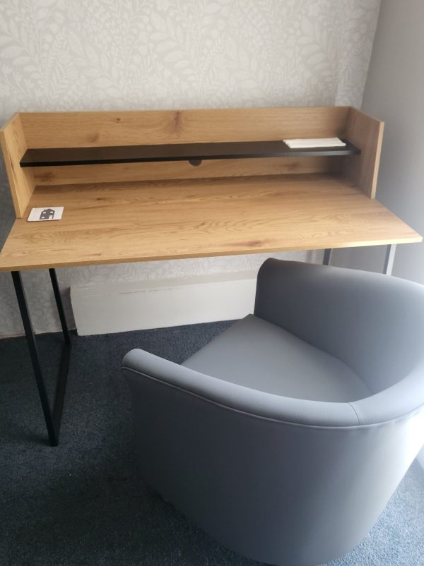 Grey bucket chair at a clean wooden, modern, steel-framed desk: an 'after' picture of the counselling room at the Oak Tree Centre